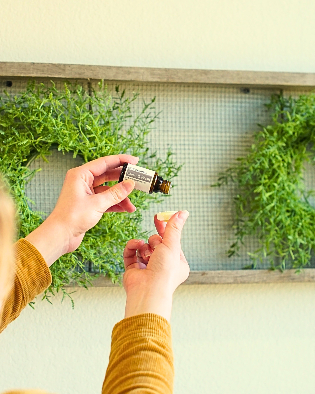 Hand dropping essential oil into a Cleaning Bomb, part of a natural cleaning product and bathroom cleaner bomb, safe, eco-friendly toilet cleaner bomb for cleaning